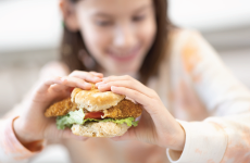 a student holding a chicken sandwich and smiling