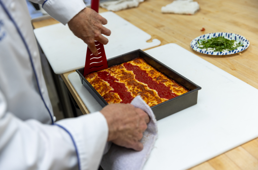 Chef cutting into Detroit style pizza