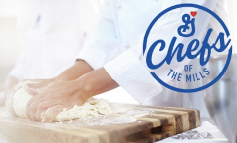 Chef kneading pizza dough over wooden cutting board with the Chefs of the Mills logo on the top right corner.