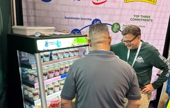 General Mills Foodservice booth at IFPA 2023. Employee talking to a booth visitor next to sample station of displayed Yoplait and Nature Valley parfaits.