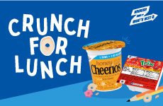 Solutions that boost participation. Crunch for Lunch. Nourish Kids for What’s Next logo. Honey Cheerios cereal cup, Trix cereal package, illustrated pencil and cereal pieces on blue background.