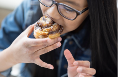 Student taking a bite out of a cinnamon roll
