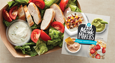 Sliced grilled chicken and tomato salad with a side of dressing in a cardboard to go box.