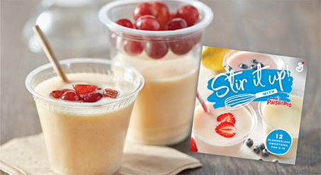 Small, clear plastic cup filled with a blenderless smoothie and sliced red grapes on top with a straw, next to a larger, clear plastic cup filled halfway with a blenderless smoothie and whole red grapes on top.