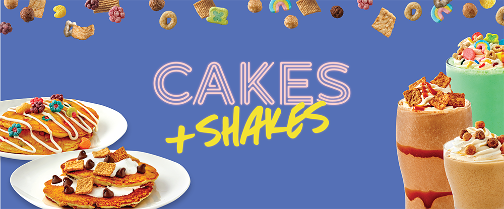 Two plates with stacks of pancakes topped with cereal, next to three milkshakes topped with cereal, and a variety of cereal pieces floating along top.