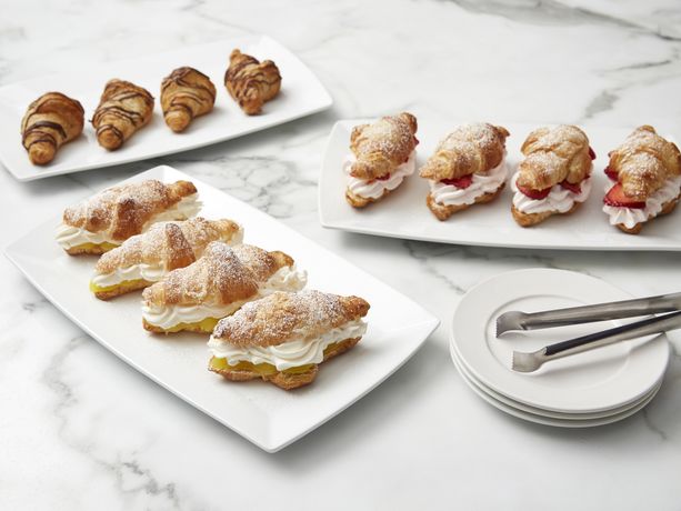 A variety of croissants on white plates on marble counter