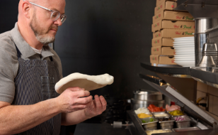 A person tossing dough for a small pizza. 