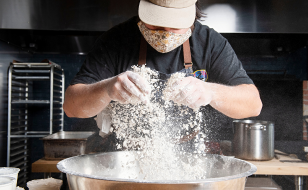 A chef sifting flour into a bowl.