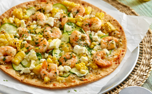 A pizza with shrimp and corn on it.