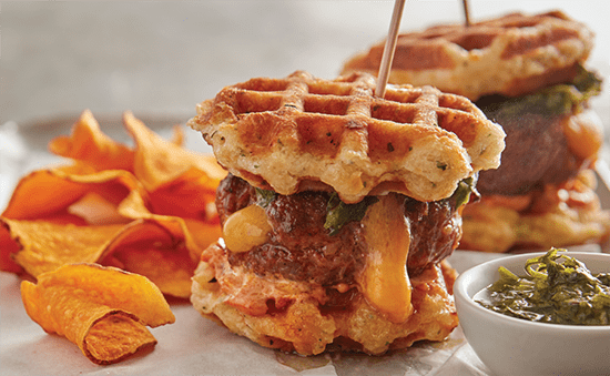 Waffle-biscuit burgers with melty cheese, chimichurri sauce and chips on the side.