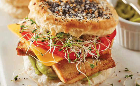 Tofu, cheese, tomato and sprouts biscuit sandwich topped with pepper and salt