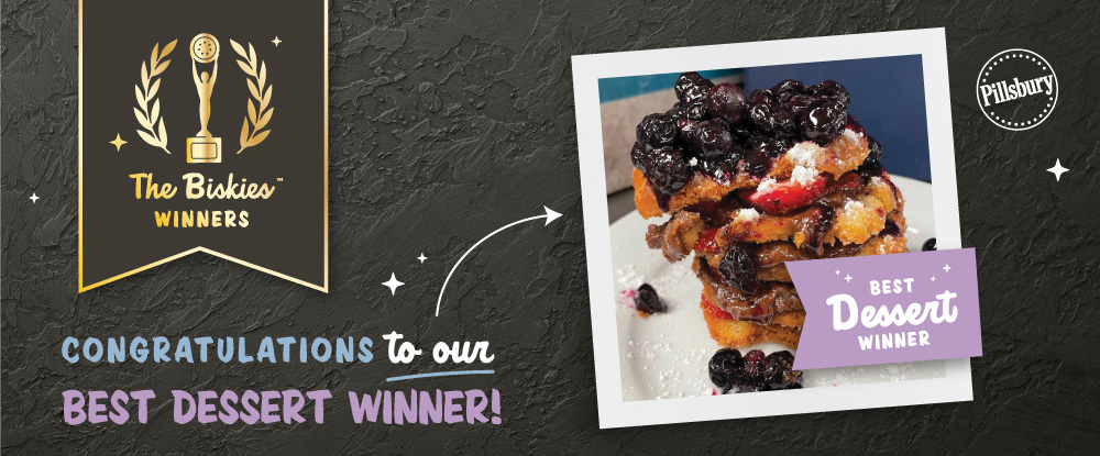 “Congratulations to our Best Dessert Winner” written underneath a black award banner with gold font reading “The BiskiesTM Winners” with an arrow pointing to an image of a biscuit topped with chocolate buttercream, and blueberry and strawberry compote.
