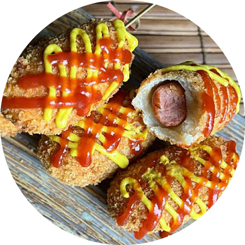 Korean biscuit wrapped hot dogs with yellow and red condiments on top