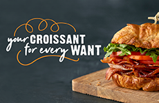 A croissant sandwich sitting on a wooden cutting board