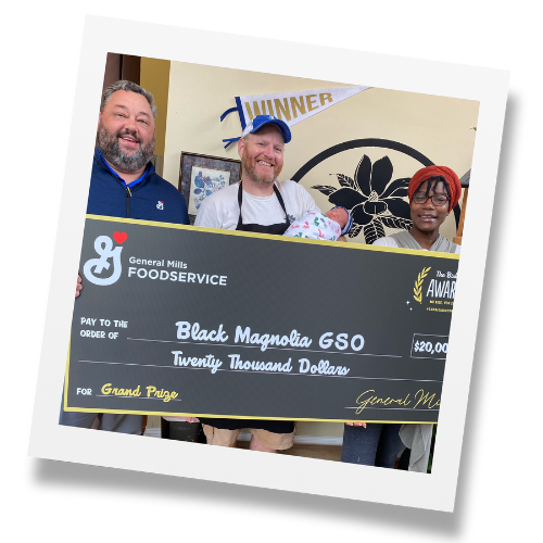 Group three adults gather around large black check made out to Black Magnolia for $20,000.